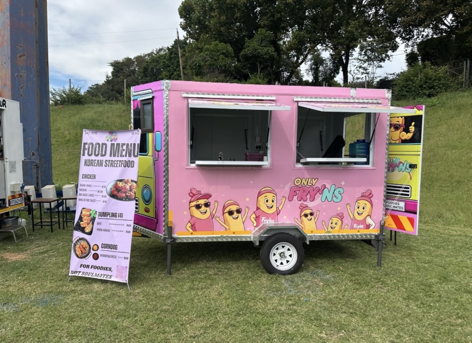 The pink ONLY FRY'NS food trailer parked on grass with its menu board out